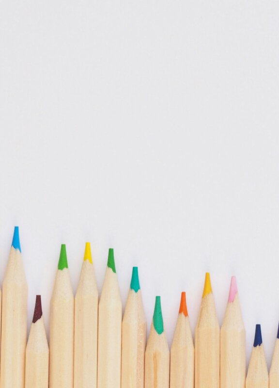 viele verschiedene Buntstifte liegen aufgrereit auf einem Tisch